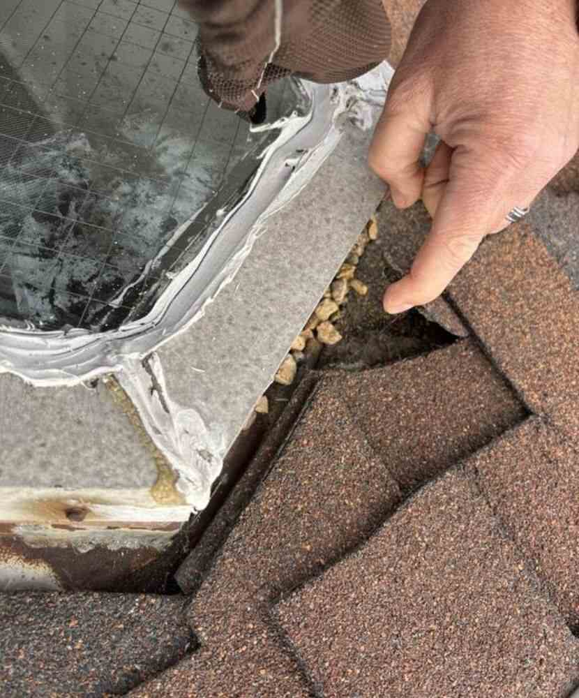 A man pointing to roof damage near a chimney on a tiled roof